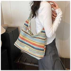 Detail of colorful striped woven hobo bag with green leather trim and bead charms