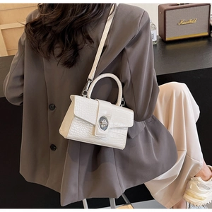 Detail shot of white crocodile-embossed leather handbag with silver metallic turn-lock clasp