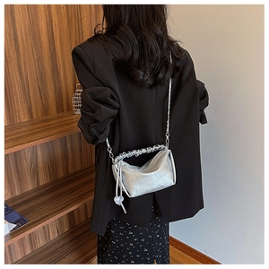 Détail du sac argenté plissé avec finition métallique et bandoulière en chaîne