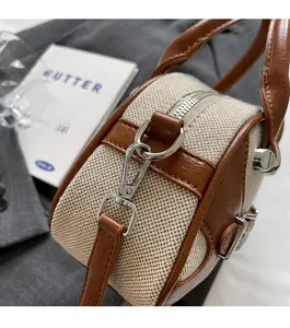 Detailed view of canvas and brown lychee leather stitching with silver metal zipper