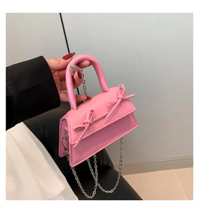 Detail of pink leather mini flap bag featuring symmetric bows and a silver chain strap