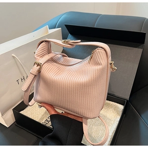 Détail du sac à main plissé rose clair avec texture ondulée et ferrures dorées