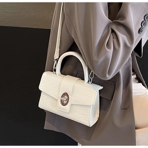 Detail shot of the white crocodile embossed PU leather crossbody bag with silver twist lock