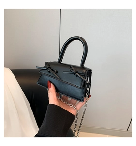 Detail of mini black ballet core handbag with dual bows and silver chain strap