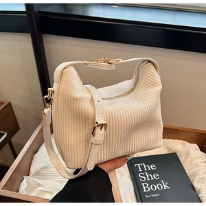 Vue détaillée de la texture du sac plissé crème avec fermetures dorées