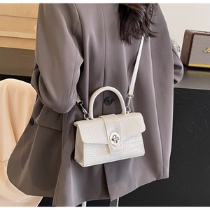 Detail of white crocodile pattern crossbody bag featuring silver metallic rotating lock