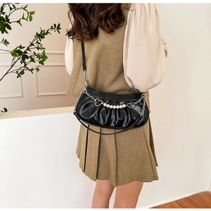 Détail du sac à bandoulière plissé noir avec motif crocodile et chaîne perle et cœur