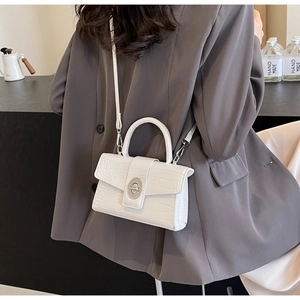 Detailed view of white crocodile pattern square bag with silver ring lock on a model