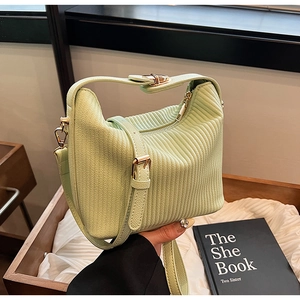 Détail d'un sac à main plissé vert clair avec ferrures dorées et texture matelassée