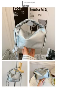 Détail du sac argenté à poignée plissée avec texture florale et bandoulière chaîne