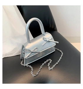 Detailed view of silver metallic mini bag with bow accents and delicate chain strap