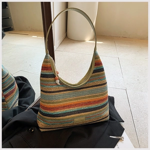 Detailed texture of bohemian rainbow striped woven tote bag with a decorative bead charm
