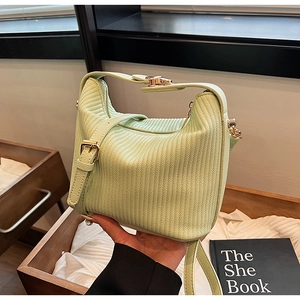 Détail du sac à main vert clair à rayures avec boucle dorée et texture en similicuir