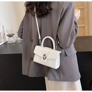 Close-up of white crocodile pattern shoulder bag with silver oval twist lock and handle