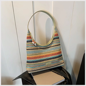 Close-up of colorful striped woven tote bag with green leather handle and beaded tassel
