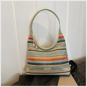 Detail of colorful striped woven tote bag with green leather handle and bead charm accessory