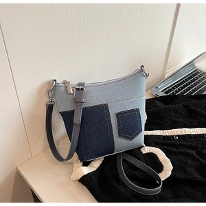 Detail der blau gemusterten Denim-Umhängetasche mit Minitasche und Metallreißverschluss