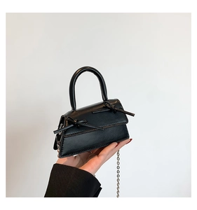 Detailed view of mini black ballet-style crossbody bag with dual bow accents and chain strap