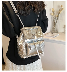 Detail of silver quilted backpack with heart buckle and chain straps on model