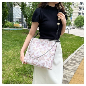 Detail der weißen Schmetterlings-Stofftasche mit Silberkette im Garten im Freien