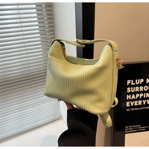Détail d'un sac à main vert clair avec plis verticaux et garnitures métalliques dorées