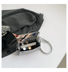 Detail showing the spacious interior of the silver metallic quilted bag with essentials