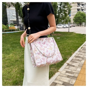 Detail der weißen Stofftasche mit Schmetterlingsdruck und Holzperlen-Schultergurt