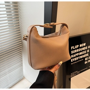 Détail du sac plissé beige clair montrant le grain vertical et la boucle dorée