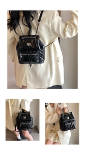 Detail of black quilted chain backpack featuring heart metal lock and glossy finish
