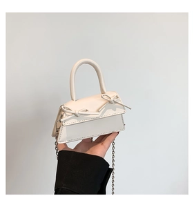 Detailed view of mini cream handbag with ribbon bows and silver chain strap