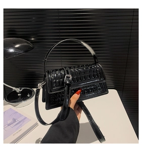 Close-up of black crocodile embossed patent leather handbag with polished silver hardware
