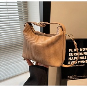 Détail d'un sac à main plissé beige avec texture en accordéon et garniture dorée