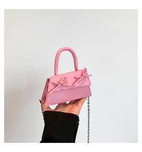 Close-up of mini pink leather bag with twin bows and silver metal chain strap