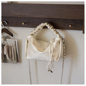 Détail du sac nuage plissé crème avec poignée souple et bandoulière en chaîne