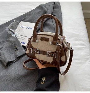 Detail of vintage canvas tote with contrast leather trim, buckles and metal studs