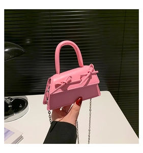 Detail of pink mini trapezoid handbag with sweet bow decoration and silver chain strap