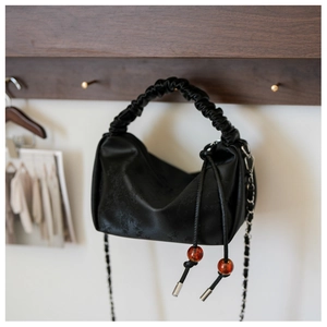 Détail du sac à main plissé noir avec cordon en perle d'ambre et bandoulière chaîne