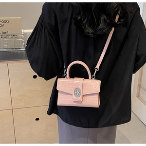 Pink crocodile-embossed mini crossbody bag with metal twist lock shown on model