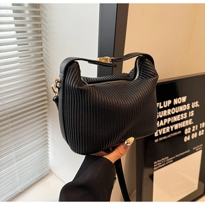 Détails d'un sac à main plissé noir avec boucles dorées et éclairage d'ambiance chic