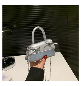 Detail of silver metallic handbag featuring silk-like texture and dual bow accents