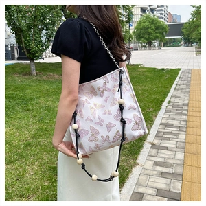 Detail des Holzperlenriemens und der Blumenstickerei auf einer weißen Jacquard-Tasche