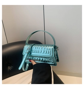 Detail of teal crocodile embossed glossy texture and metallic buckle on handbag
