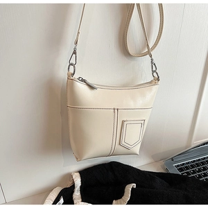 Detail einer cremefarbenen Ledertasche mit dunkler Kontrastnaht und silbernem Metall