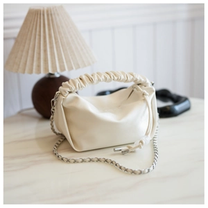 Détail d'un sac à main plissé crème avec design en forme de nuage et chaîne argentée