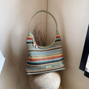 Colorful rainbow striped crochet tote bag with light green leather strap on stone base