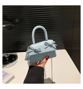Detail of light blue mini trapezoid bag with bow accents and silver chain strap