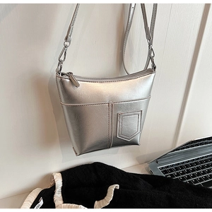 Detailansicht einer silbernen Metallic-Schultertasche mit Trapezform und Reißverschluss