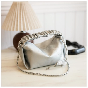 Détail d'un sac à main plissé argenté avec chaîne métallique et perles sur le cordon