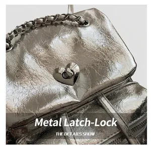 Macro shot of silver textured leather backpack with heart-shaped lock and chain strap