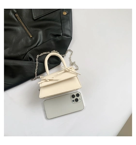 Detailed top view of a cream mini bow trapezoid bag with silver chain strap and top handle